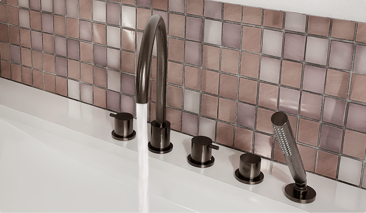 Detail van een badrand met elegante bronzen mengkranen, handdouche en sierlijke mozaïektegels in zachte roze en paarse tinten. Een luxueuze afwerking met metallic accenten in x²o badkamers.