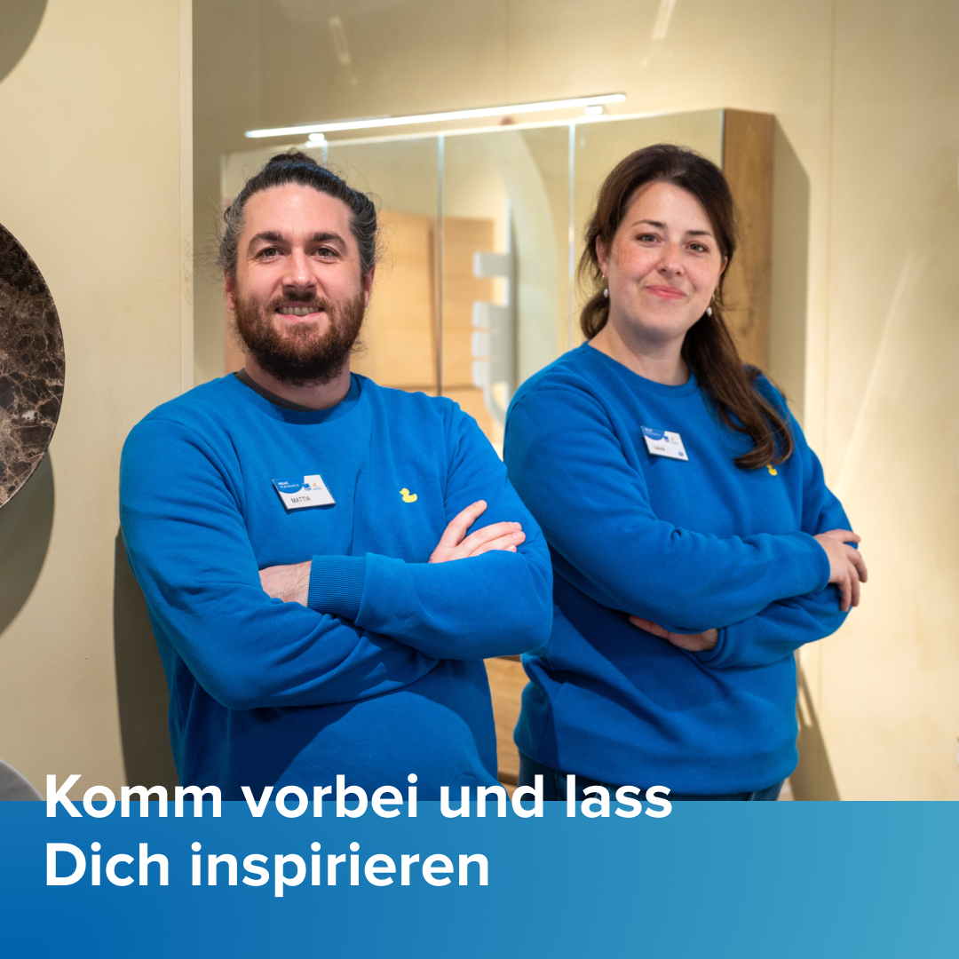 Zwei Mitarbeitende von x²o Badezimmer stehen mit verschränkten Armen in einem Badezimmer-Showroom, tragen blaue Pullover und stehen vor einem beleuchteten Spiegelschrank und Badmöbeln. Unten im Bild steht der Text „Komm gerne vorbei und lass dich inspirieren“.
