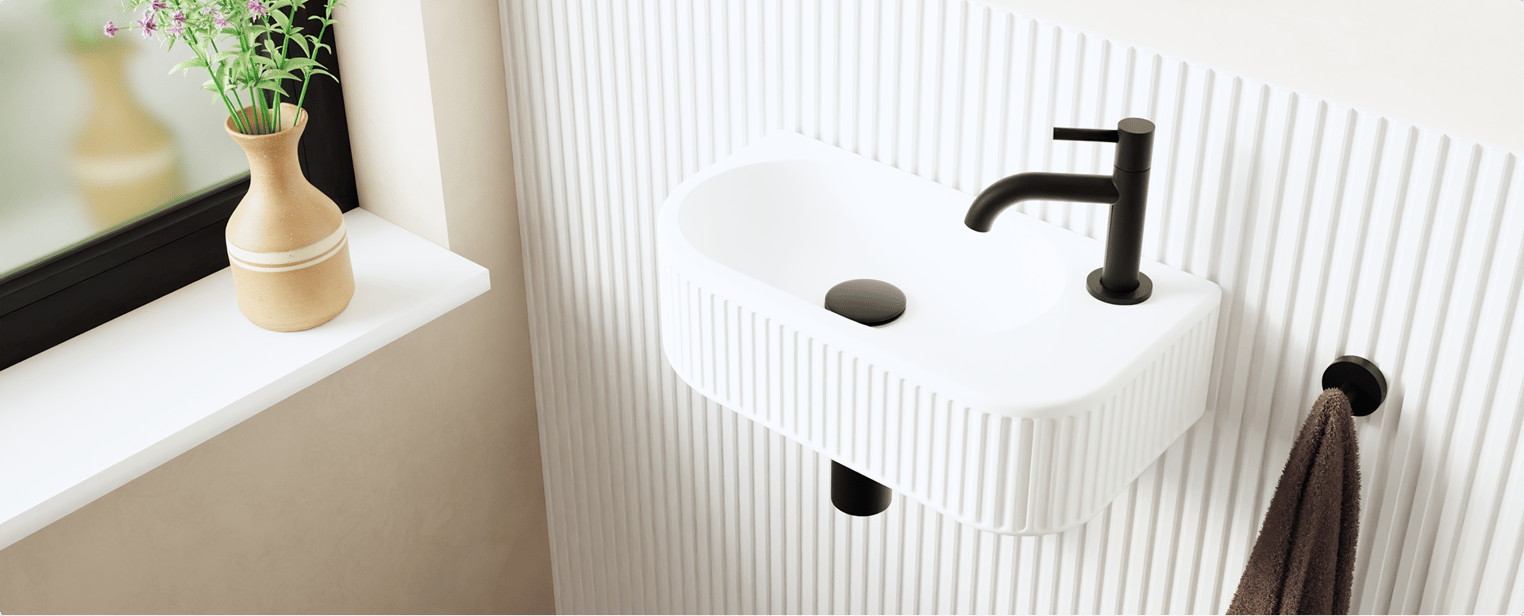 Weißes geriffeltes Wandwaschbecken mit integrierter Waschschale, mattschwarzem Wasserhahn und schwarzem Pop-up-Ablauf, montiert an einer weißen geriffelten Wand, in einem minimalistischen Badezimmer mit dekorativer Vase auf der Fensterbank.