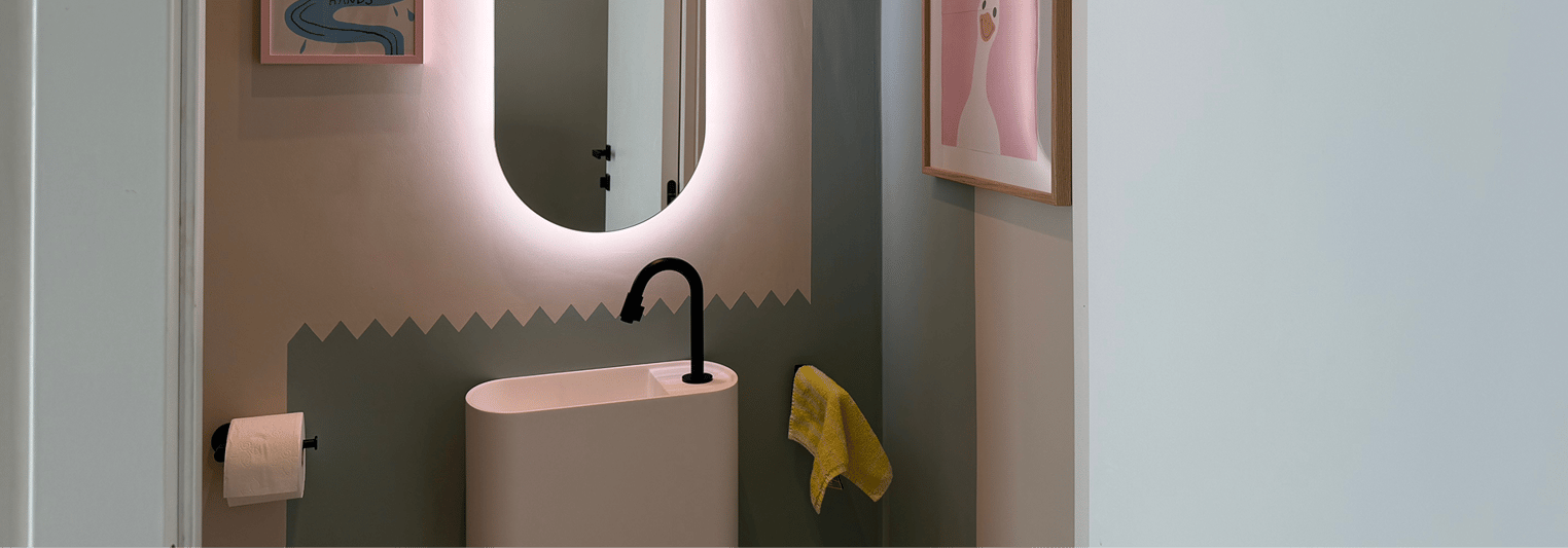 Detailansicht eines stilvollen Toilettenraums von x²o Badezimmer mit Balmani Livo Waschbecken, schwarzer Armatur und beleuchtetem Spiegel.