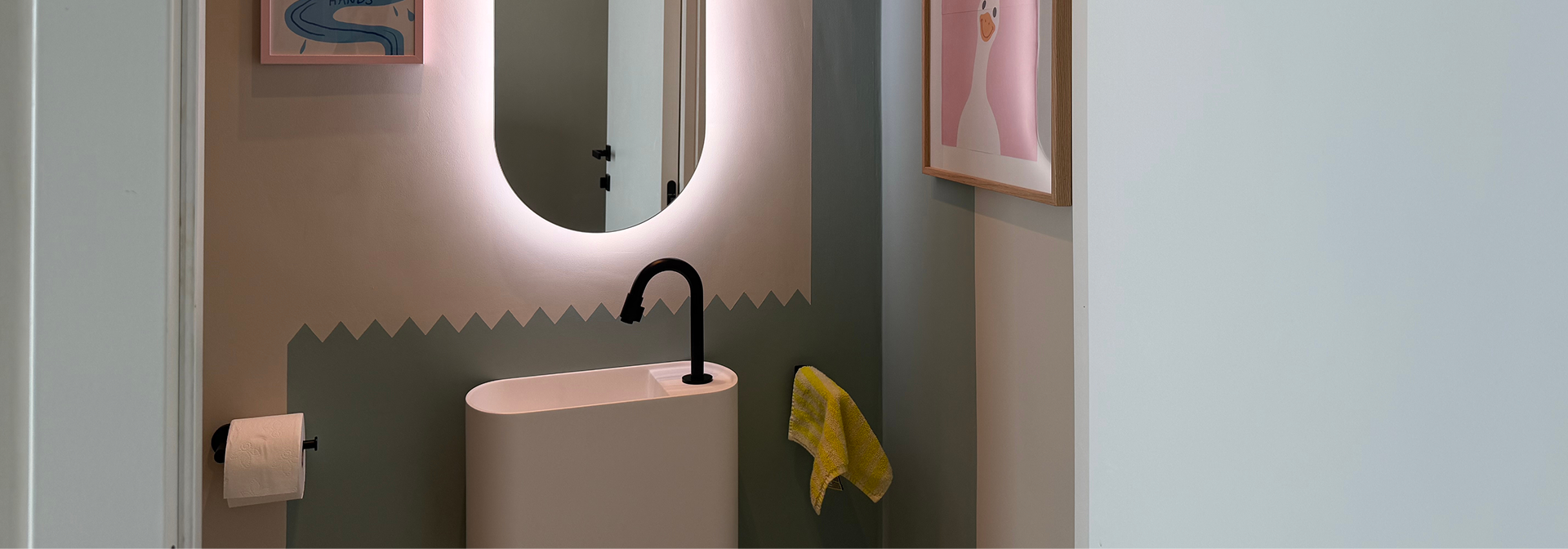 Detailansicht eines stilvollen Toilettenraums von x²o Badezimmer mit Balmani Livo Waschbecken, schwarzer Armatur und beleuchtetem Spiegel.