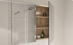 Openstaande spiegelkast van x²o badkamers boven een douchegedeelte, met zicht op houten legplanken en badkameraccessoires zoals flessen en verzorgingsproducten. De spiegeldeur combineert opbergruimte met een strak design.