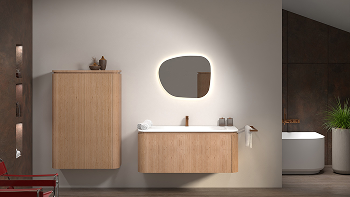 Zwevend badkamermeubel in lichte houtafwerking met geïntegreerde wastafel en asymmetrische spiegel met indirecte verlichting, gecombineerd met een hoge kolomkast en vrijstaand bad op de achtergrond, in een badkamer van x²o badkamers.