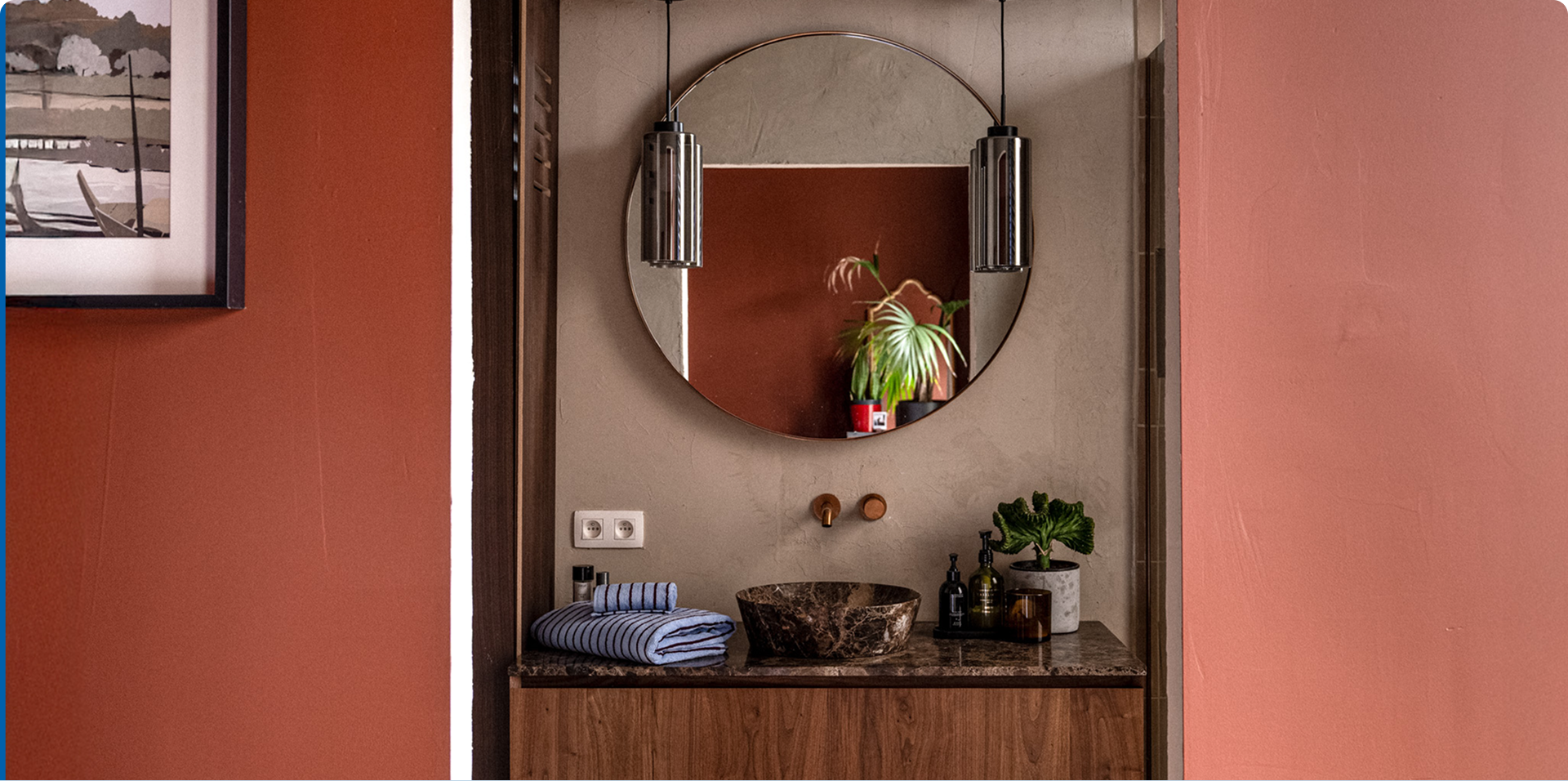 Marmeren waskom op houten meubel onder ronde spiegel met verlichting.