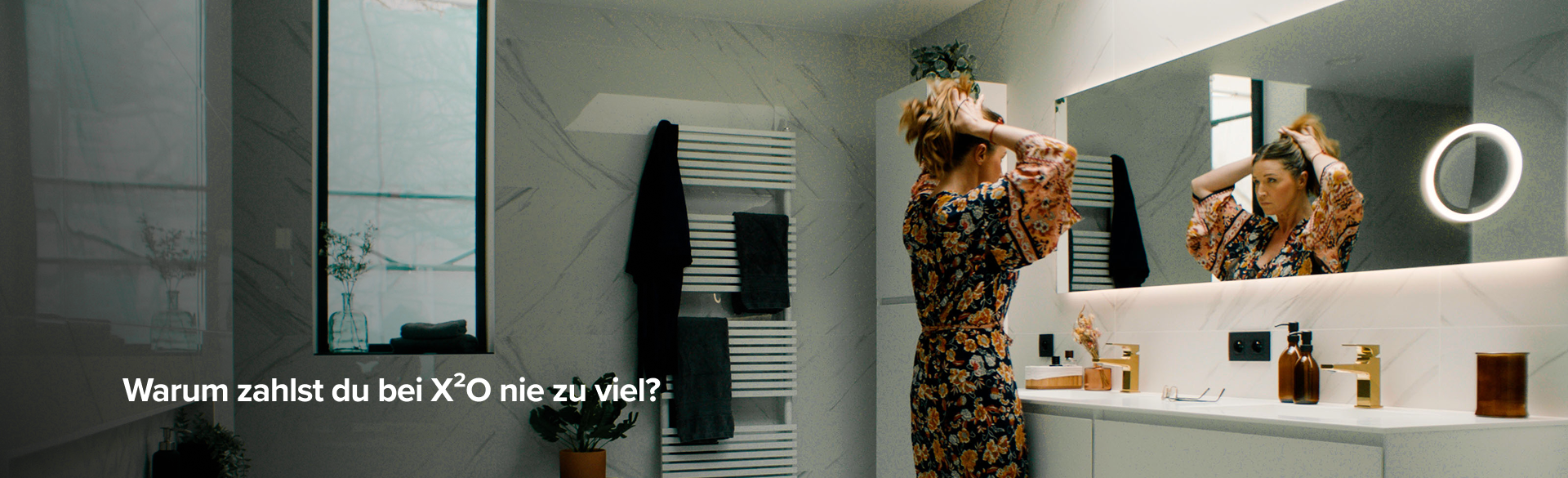 Frau vor dem Spiegel in einem stilvollen Badezimmer mit weißen Marmorwänden, X²O Badezimmer.