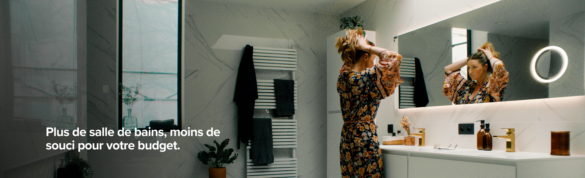 Femme devant le miroir dans une salle de bains élégante avec murs en marbre blanc, X2O salles de bains.