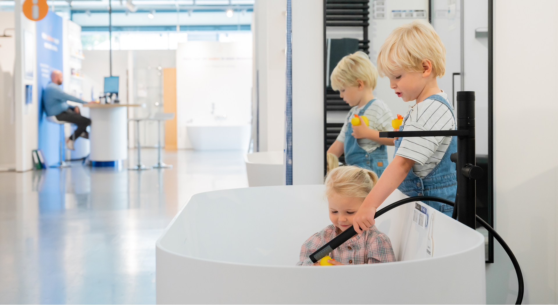 Des enfants jouent avec des jouets de bain dans une baignoire du showroom de X2O salles de bains.