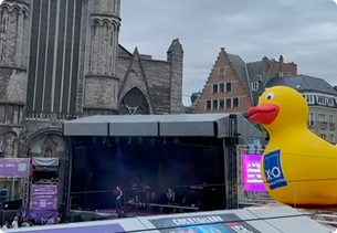 Podium op de Gentse Feesten met grote opblaasbare badeend van X²O badkamers op een plein met historische gebouwen.