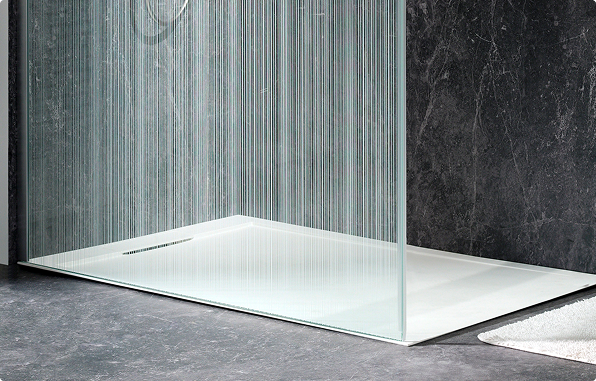 Moderne Duschwanne von x²o Badezimmer in Weiß mit flachem Einstieg und Glaswand auf dunklem Boden mit strukturierter Wand.