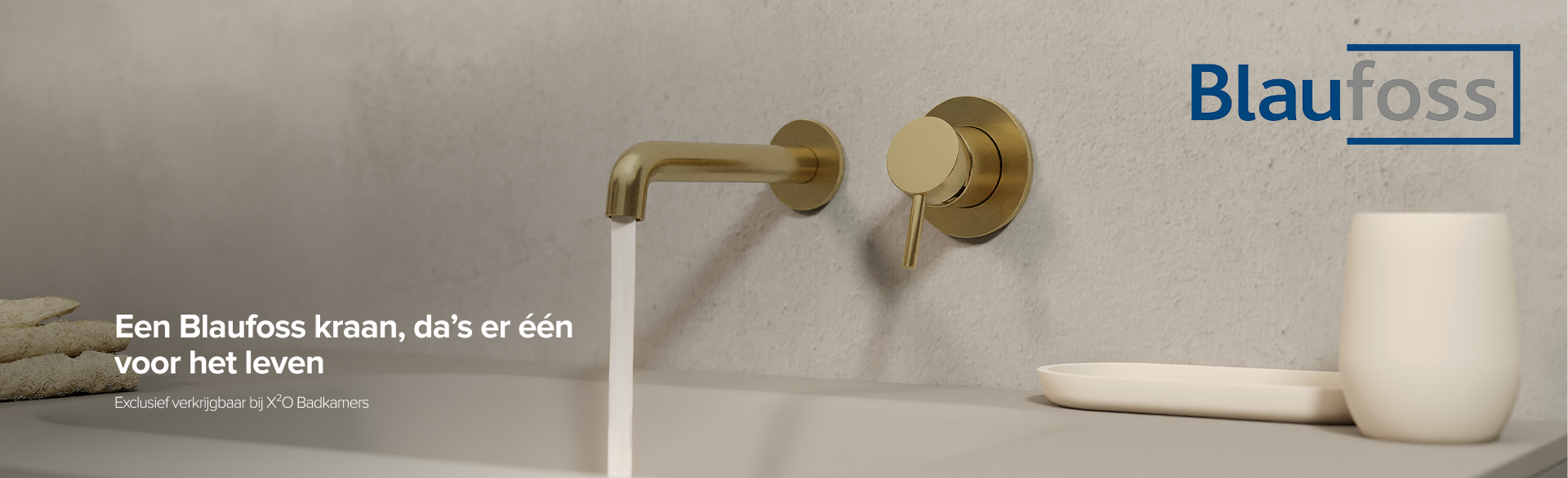 Gouden wandkraan van Blaufoss boven een wastafel met neutrale betonlook achterwand – exclusief verkrijgbaar bij X²O Badkamers.