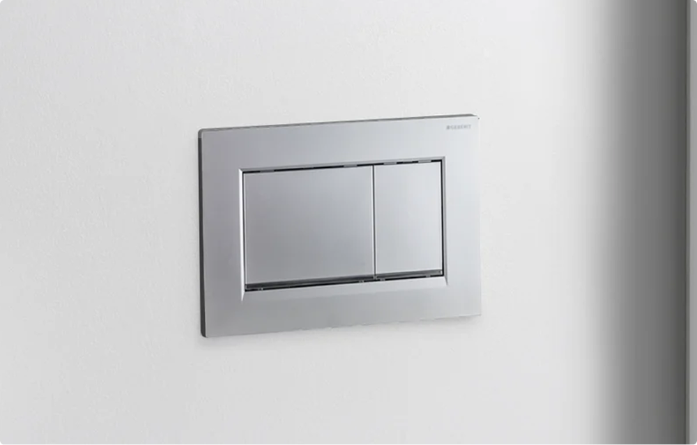 Moderne Geberit Betätigungsplatte in Chromoptik von x²o Badezimmer für die Zweimengenspülung an einer weißen Wand.