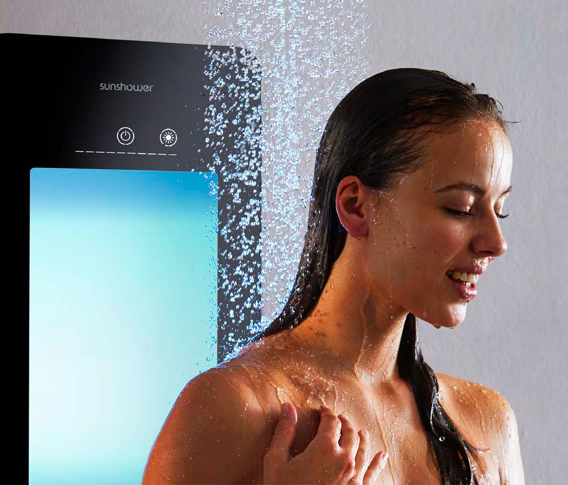 Close-up van iemand onder de douche met een zwart Sunshower-paneel dat helder blauw licht uitstraalt. Waterdruppels vallen op het lichaam. Deze geavanceerde oplossing voor x²o badkamers zorgt voor een ontspannende douche-ervaring.