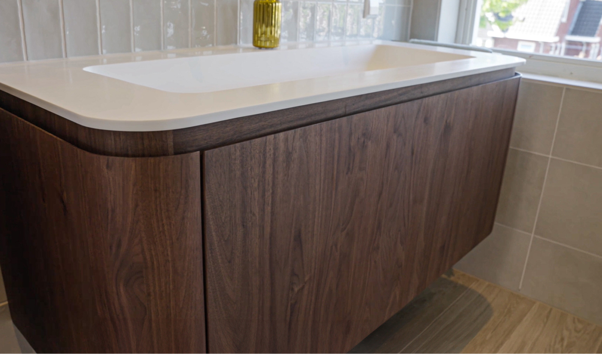 Nahaufnahme eines weißen Waschbeckens mit abgerundeten Ecken und eines dunkelbraunen Badmöbels mit abgerundeter Front, gestaltet von x²o Bad.
