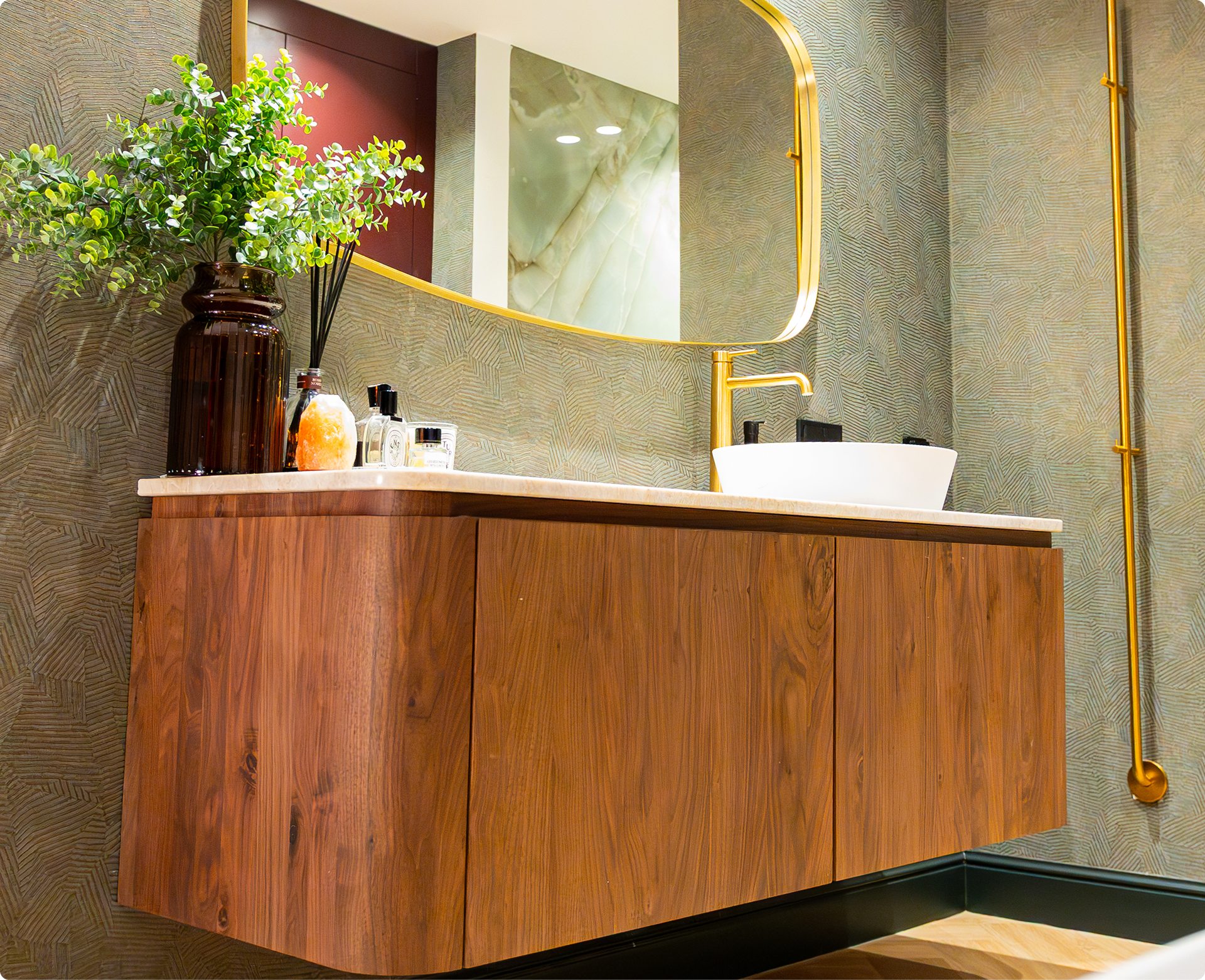 Dieses Foto zeigt ein wunderschönes Detail der x²o badkamers Ensuite: eine große ovale freistehende Badewanne mit goldener Armatur und Handtuch. Daneben stehen große grüne Pflanzen und der Boden hat eine warme Holzoptik, die den luxuriösen Look unterstreicht.