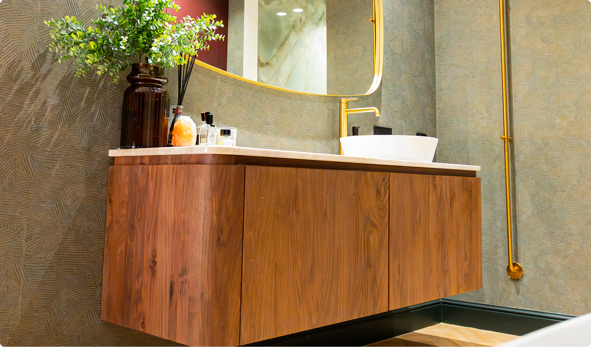 Dieses Foto zeigt ein wunderschönes Detail der x²o badkamers Ensuite: eine große ovale freistehende Badewanne mit goldener Armatur und Handtuch. Daneben stehen große grüne Pflanzen und der Boden hat eine warme Holzoptik, die den luxuriösen Look unterstreicht.