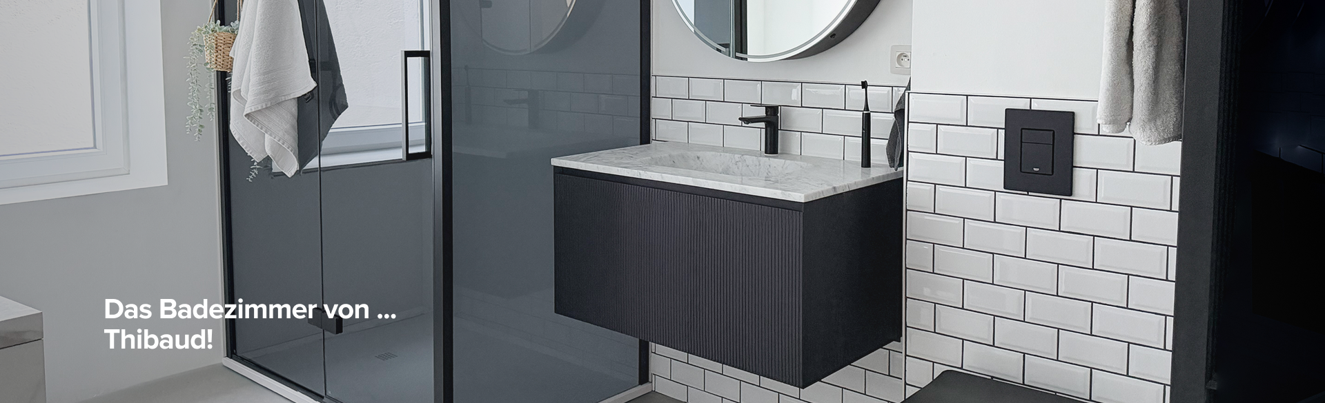 Badezimmer von x²o Bad mit Dusche, schwarzem Möbel und rundem Spiegel mit deutschem Text „Das Badezimmer von Thibaud“.