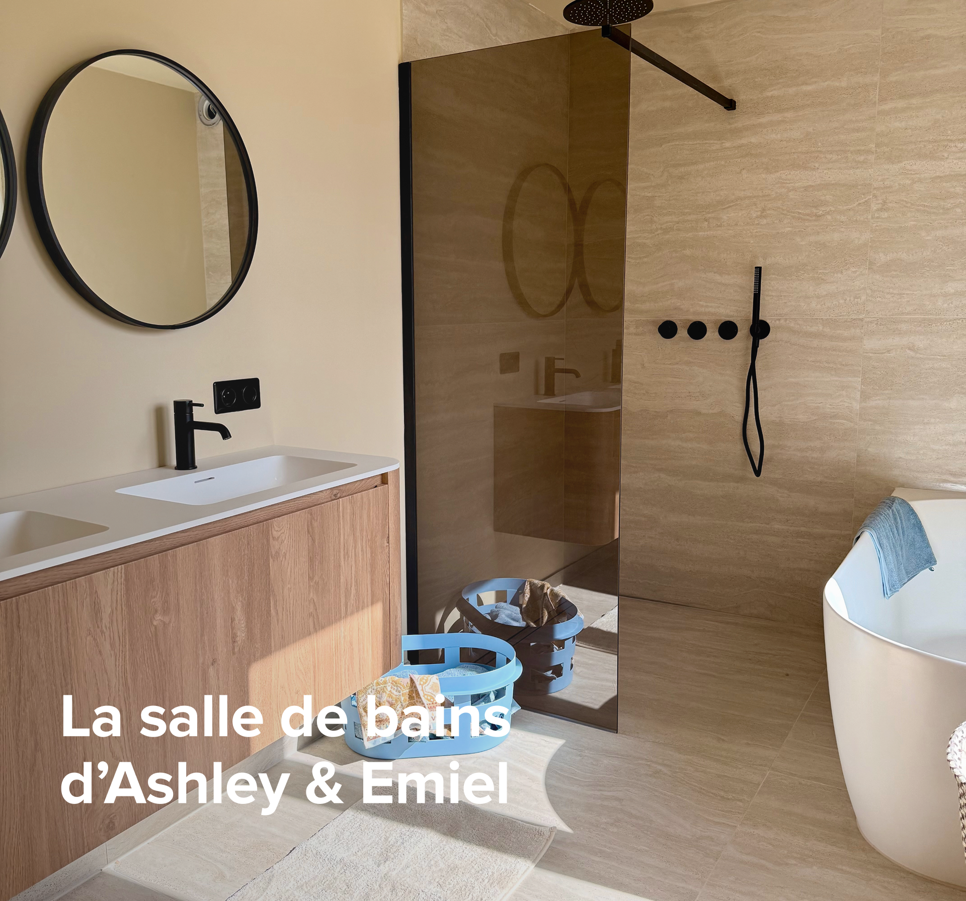 Dans cette salle de bains inspirante de x²o salles de bains, on voit l’intérieur d’Ashley et Emiel avec un meuble lavabo en bois, une douche à l’italienne avec paroi en verre et commandes noires, et une baignoire blanche autoportante avec serviette, avec le texte « La salle de bains de Ashley et Emiel » visible sur l’image.