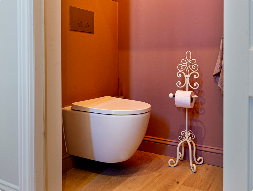 Modern Luca Varess Moreno hangtoilet van x²o badkamers in een warme toiletruimte met roze muren, gouden accessoires en sfeervolle verlichting.