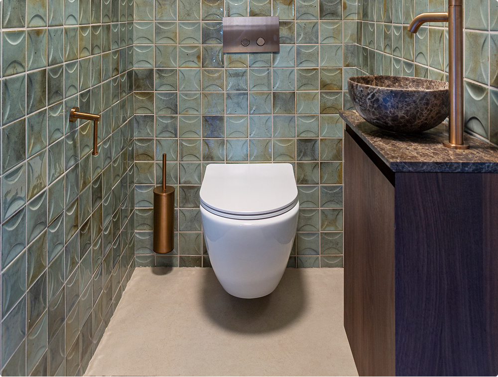 Luca Varess Moreno hangtoilet van x²o badkamers gecombineerd met groene wandtegels, donkere wastafelmeubel en gouden toiletaccessoires.