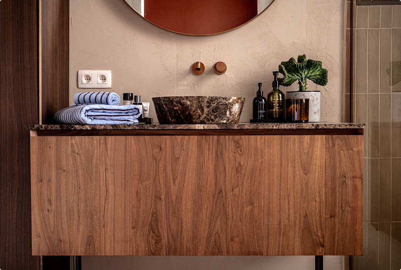Houten badkamermeubel met marmeren waskom, opgerolde handdoeken en groene plant – X2O badkamers