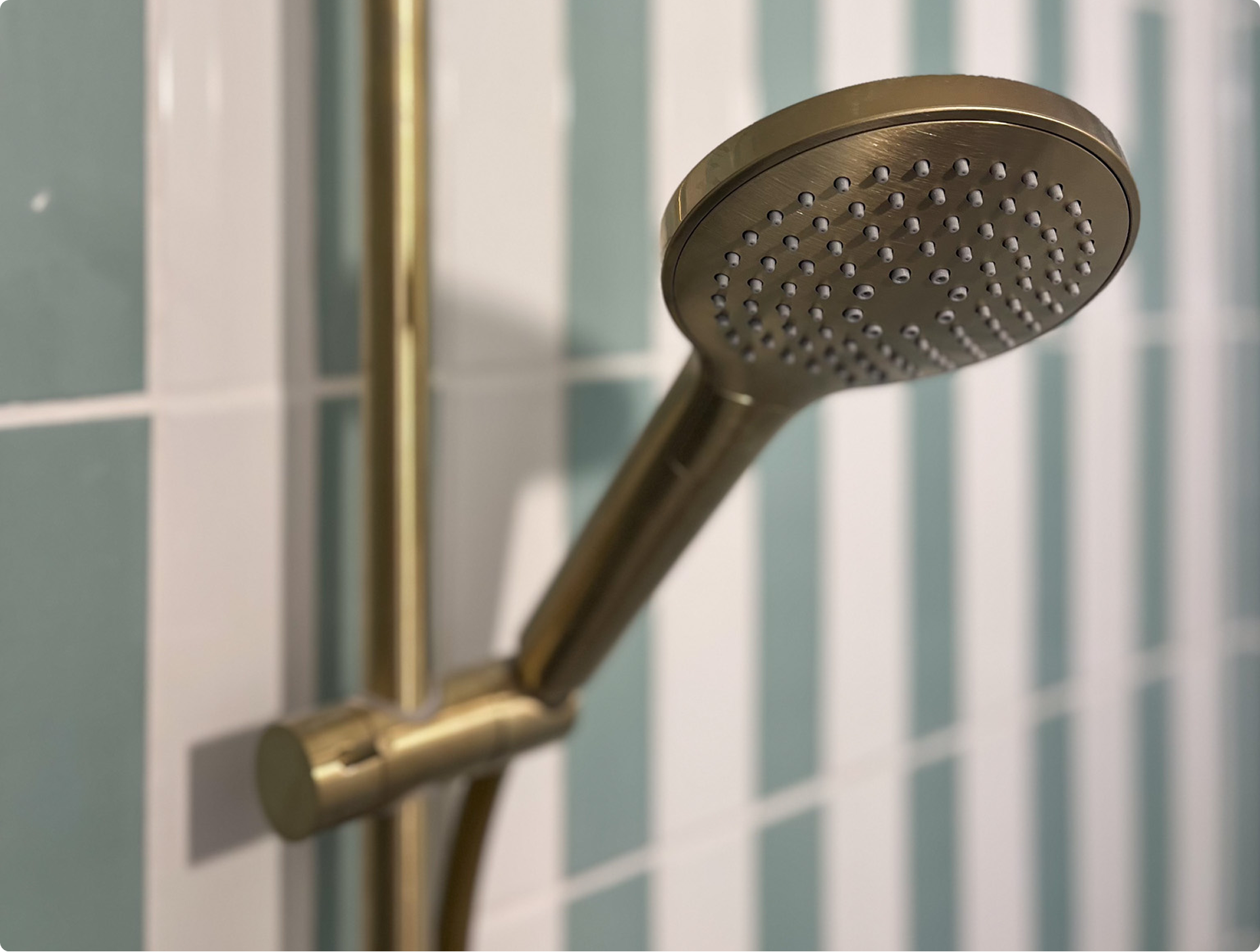 Bad-douche met gouden kraanwerk en verticale pastelgroene tegels, inclusief het vertrouwde badeendje – een creatie van x2o badkamers.