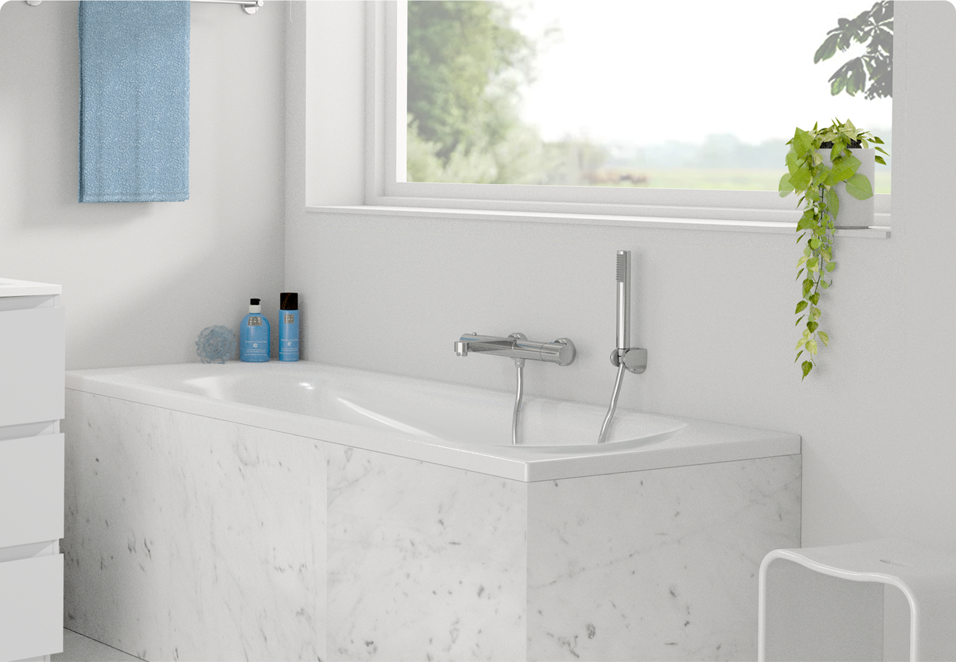 Op deze foto van x²o badkamers zie je een kleine witte ingebouwde badkuip met een witte marmeren ombouw, een chromen wandkraan met handdouche, twee blauwe flessen en een sponsje op de badrand, een blauwe handdoek aan de muur en een hangplant op de vensterbank met vrij uitzicht naar buiten.