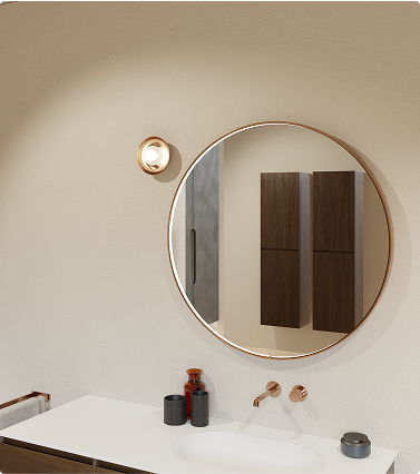 Miroir de salle de bains rond avec cadre cuivré, combiné à une vasque blanche, un meuble en bois et une applique murale – ambiance chaleureuse de x²o salles de bains.