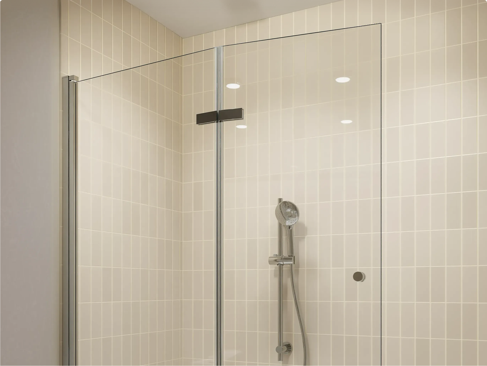 Paroi de douche en verre transparent avec profilé noir, installée devant des carreaux métro couleur crème posés verticalement et une douchette chromée, dans une salle de bains de x²o salles de bains.