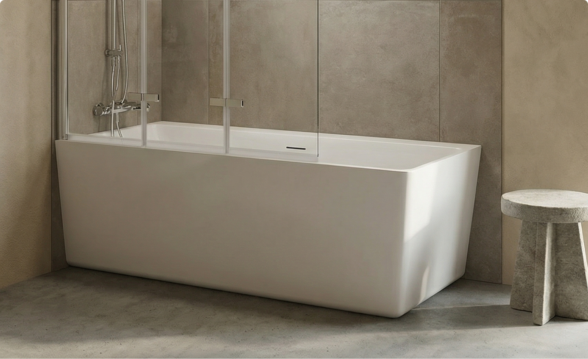 Wit hoekbad met glazen badwand en chromen douchekraan, geplaatst tegen betonlook wanden met een bijpassend betonnen krukje naast het bad, in een badkamer van x²o badkamers.