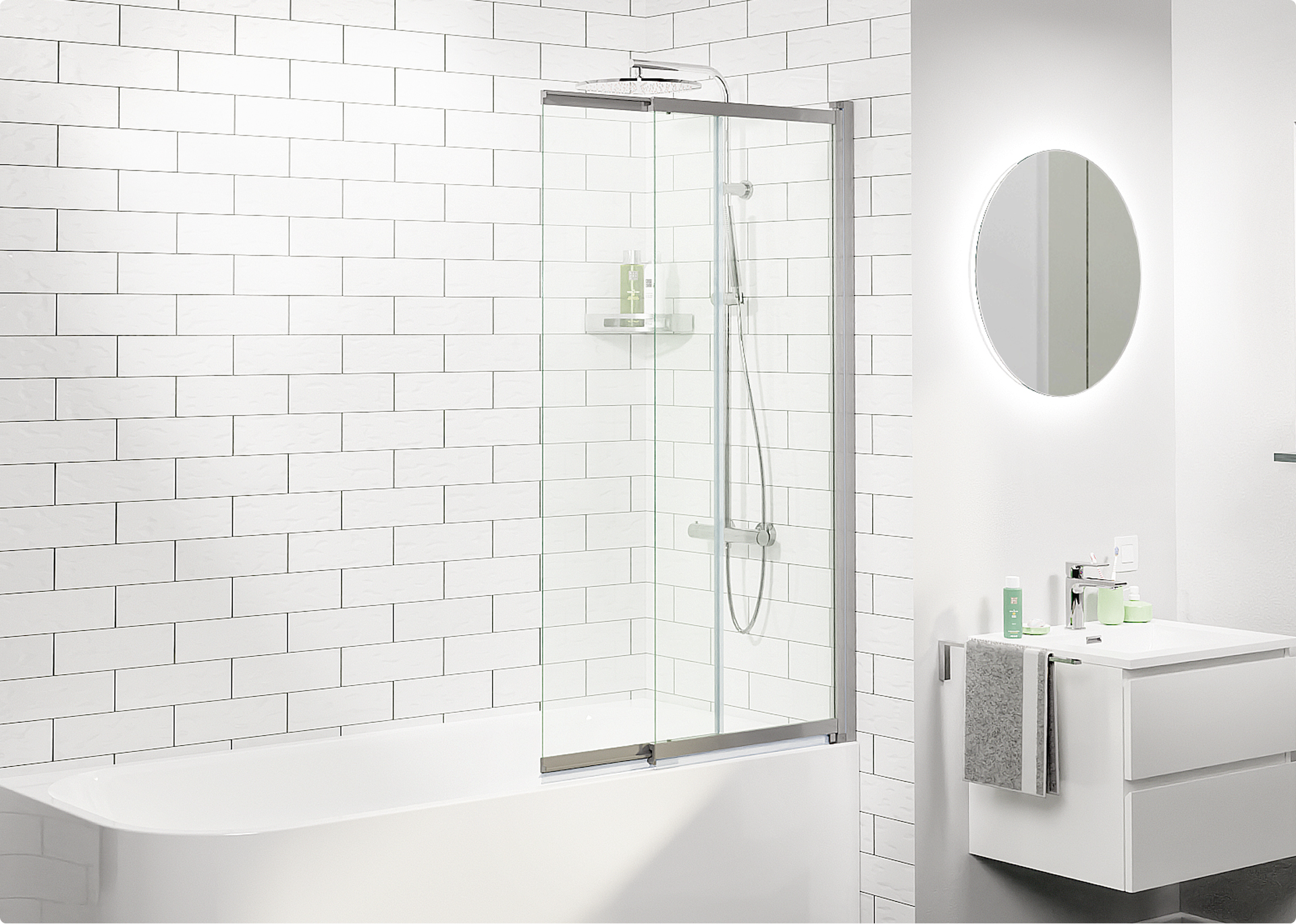 Moderne witte badkamer met ligbad en glazen badwand, witte metrotegels op de muur, regendouche met handdouche en een zwevend wastafelmeubel met ronde spiegel, ingericht met producten van x²o badkamers.