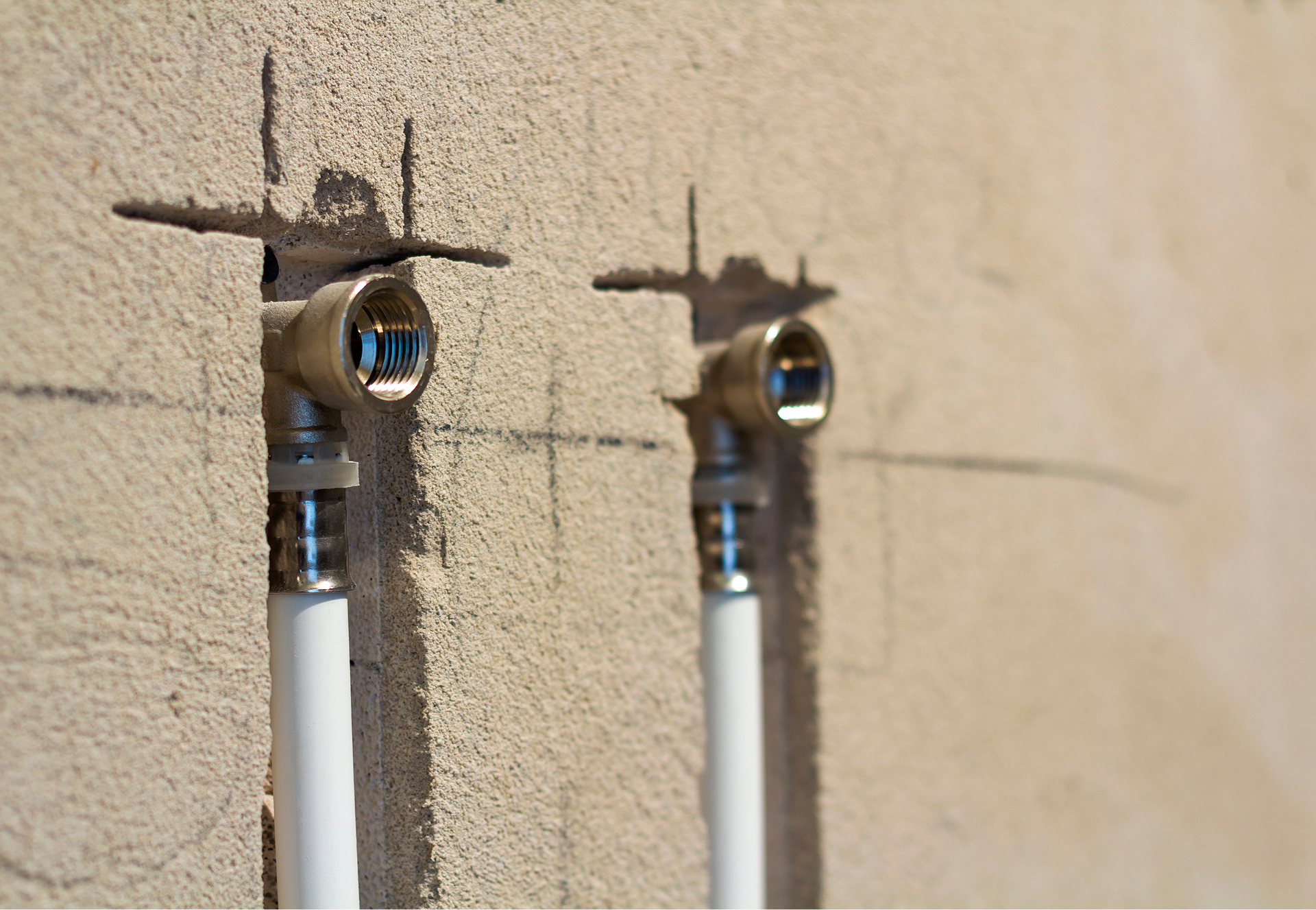 Detail van een muuraansluiting voor waterleidingen tijdens de installatie van een douchecabine bij X²O badkamers