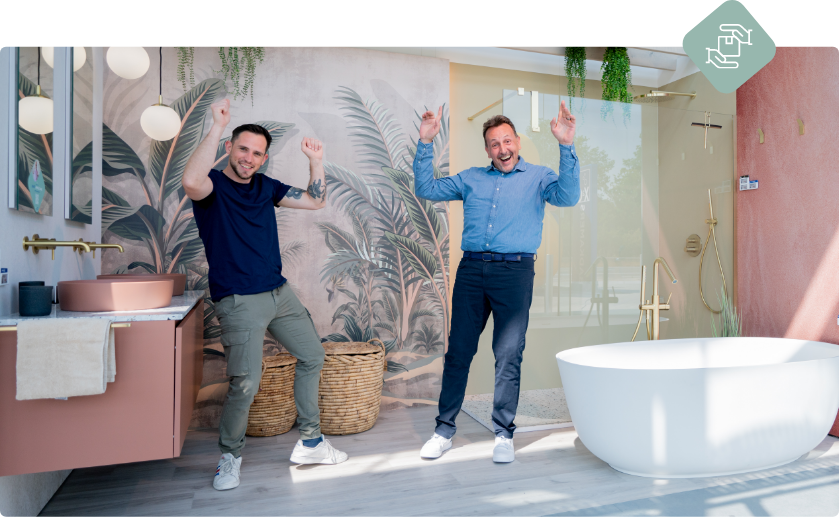 Zwei Männer jubeln in einer Showroom-Szene mit Badewanne und Dusche, als Symbol für 12 Monate kostenlose Lagerung bei x²o Badezimmer.
