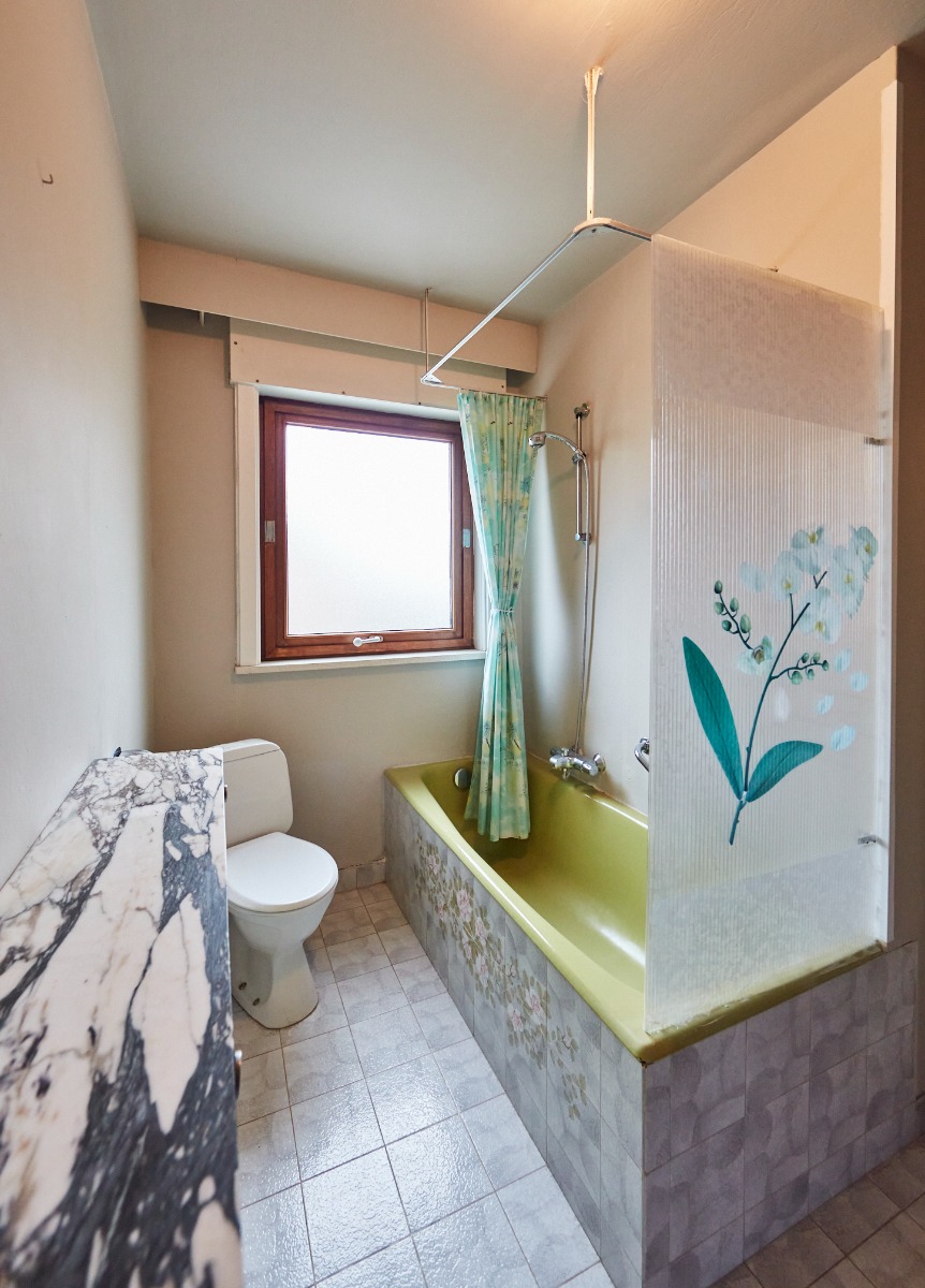 Datiertes Badezimmer mit gelber Badewanne und weißen Fliesen.