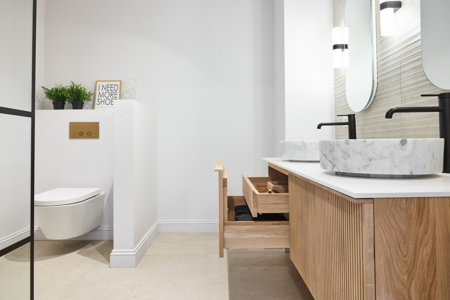 Afgewerkte badkamer met houten wastafelmeubel en marmeren waskommen.