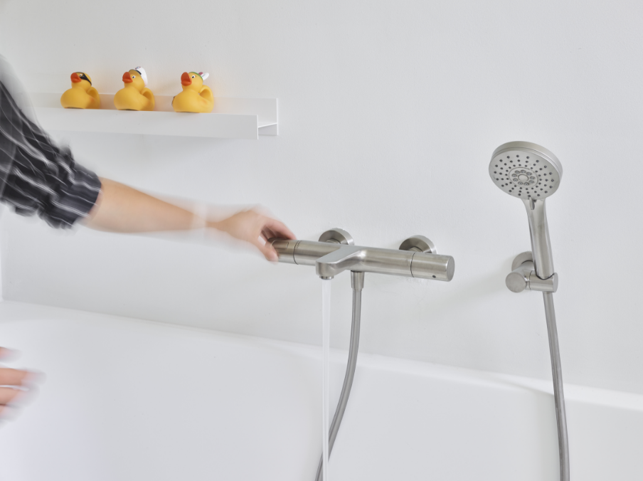 Handdouche met waterstraal gemonteerd op een witte badrand.