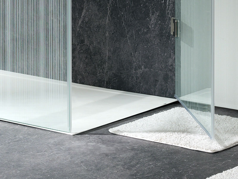 Moderne badkamer met een vrijstaand wit bad, een strak betegelde wand en een minimalistisch interieur waarin rust, licht en elegantie centraal staan.