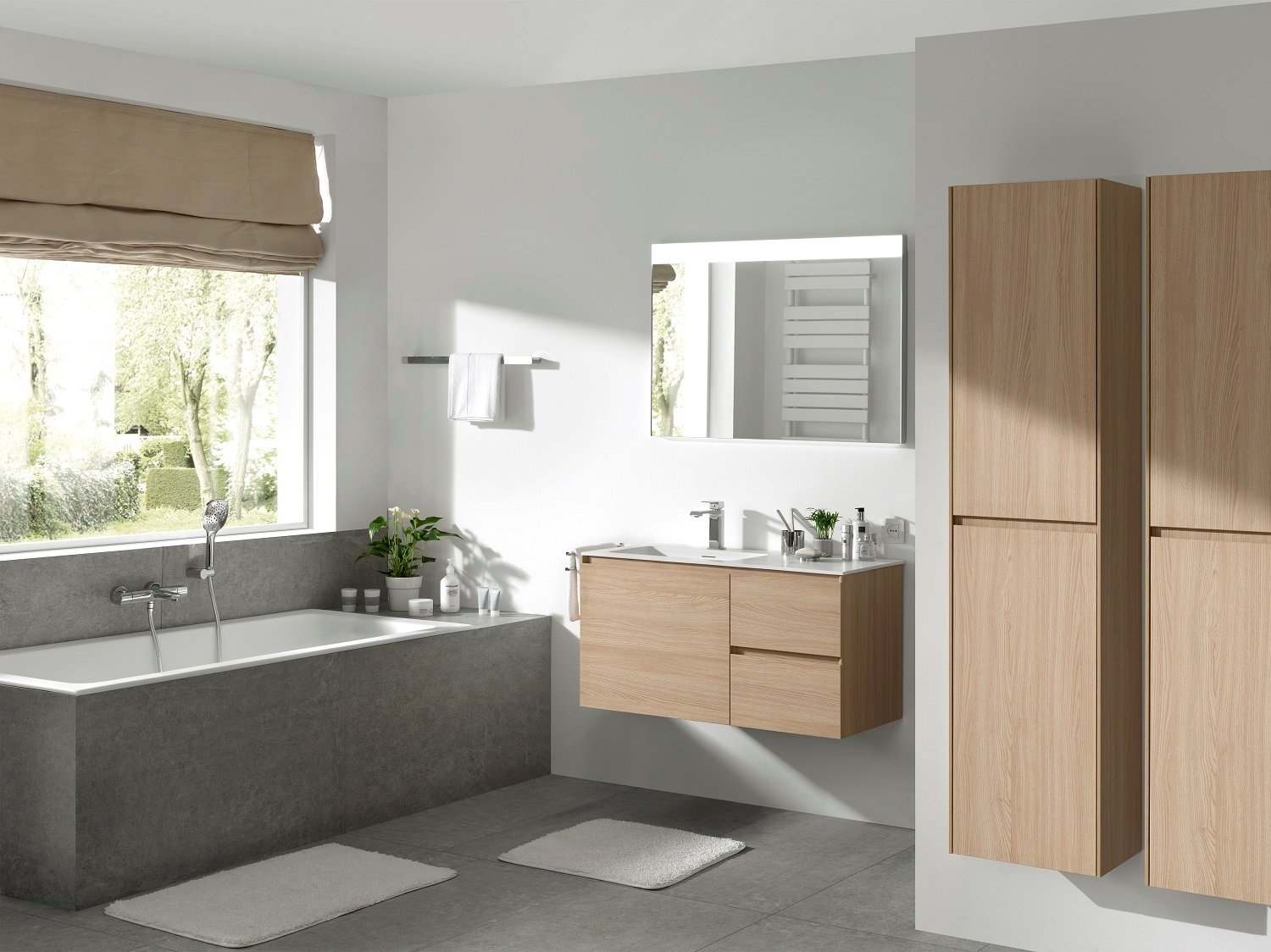 Stijlvolle badkamer met houten badkamermeubels, ligbad en grote spiegel met verlichting.