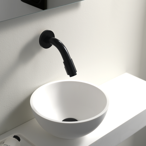 Weiße Aufsatzwaschschüssel mit schwarzer Wandarmatur.