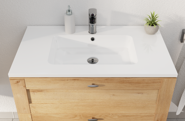 Vue du dessus d’un meuble lavabo de x²o salles de bains avec vasque blanche, bonde intégrée, robinet chromé et plante décorative.