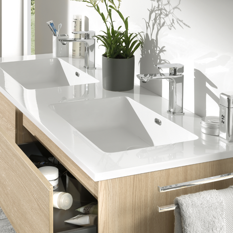 Moderne Doppelwaschtisch aus weißer Keramik mit Badezimmermöbel in Holzoptik und Aufbewahrungsschubladen.