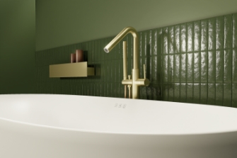 Freistehende Badewanne mit goldener Armatur und grünen Fliesen für eine elegante, natürliche Badezimmeroptik.
