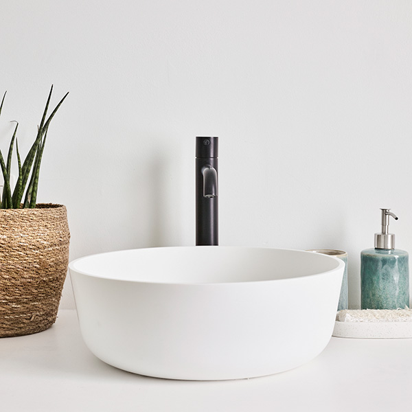  Rond, wit wastafel met een zwarte kraan op een wit blad.