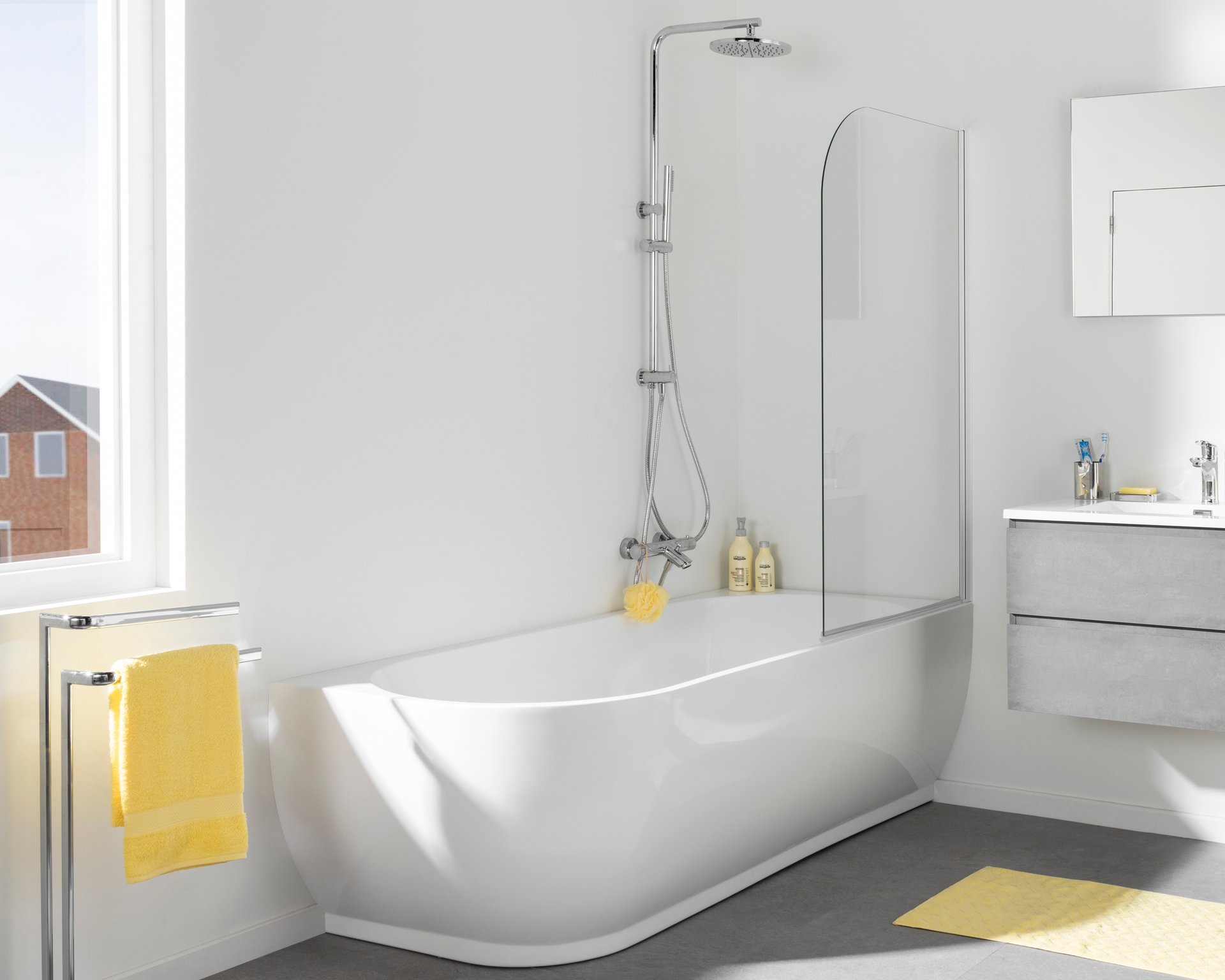 Badezimmer mit freistehender Badewanne, Glas-Duschwand, gelben Handtüchern und modernem Waschbecken.