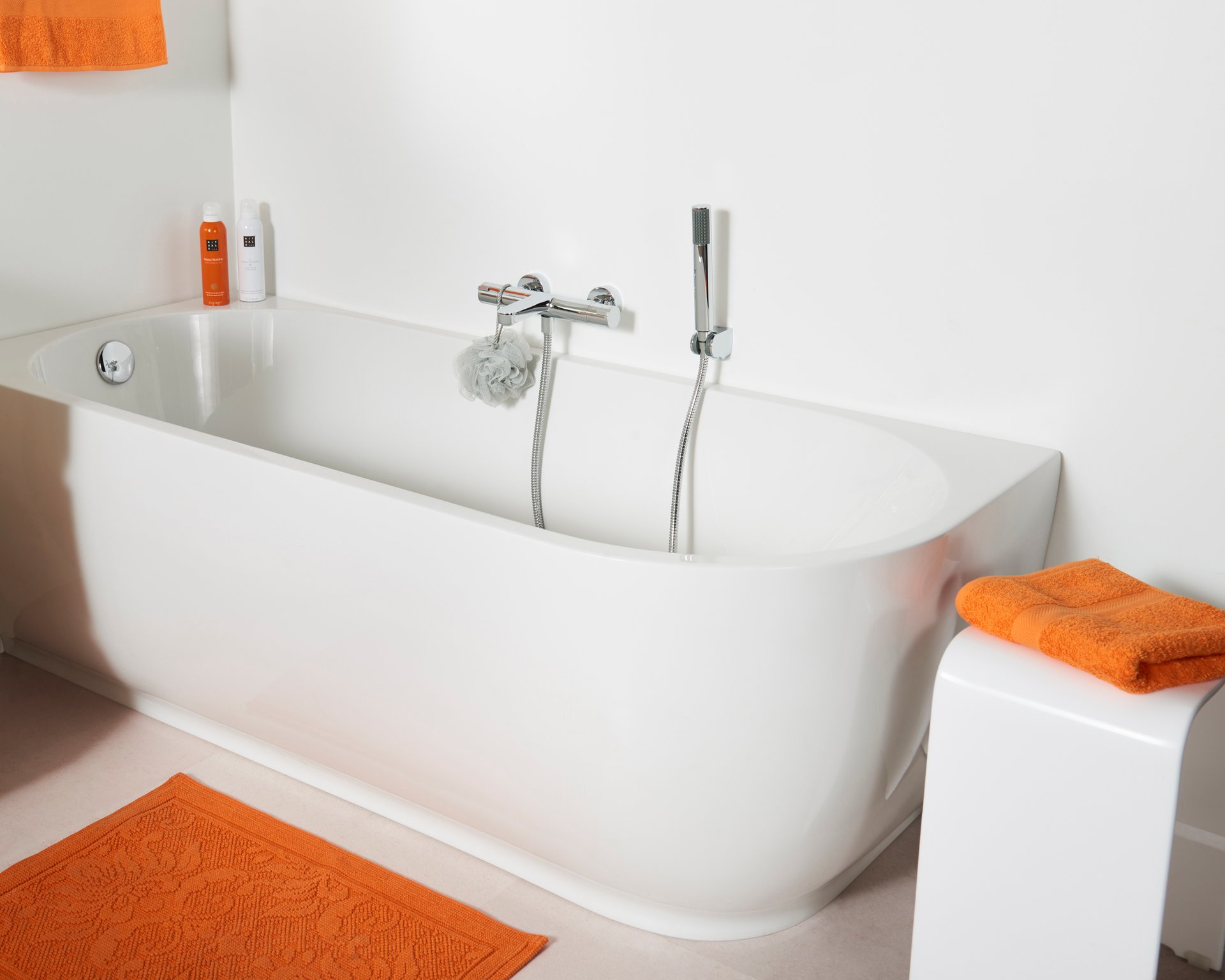 Badewanne mit Duschkopf, orange Handtüchern und modernem, minimalistischem Design.