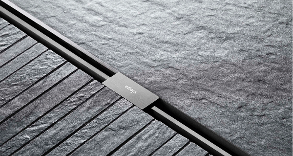 Detailaufnahme eines modernen Duschbodens mit dunklen Steinplatten und einem minimalistischen, integrierten Abfluss