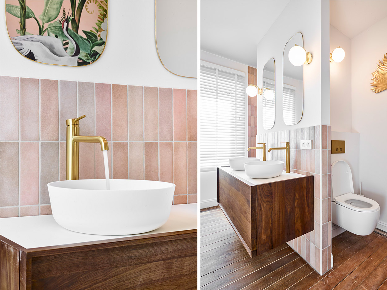Salle de bain avec deux lavabos blancs, robinets dorés, meuble en bois et toilettes séparées