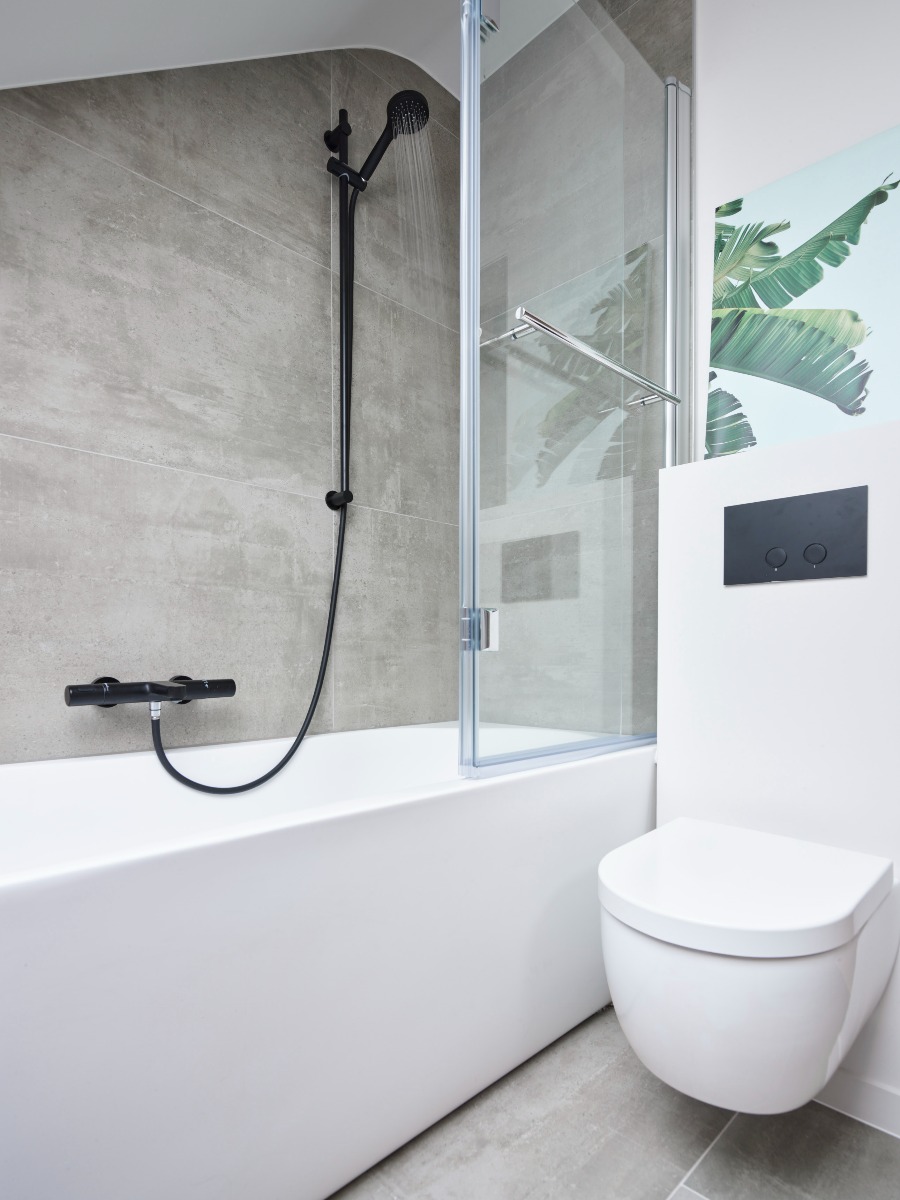 Witte badkamer met een bad en een zwarte regendouche met glazen wand.