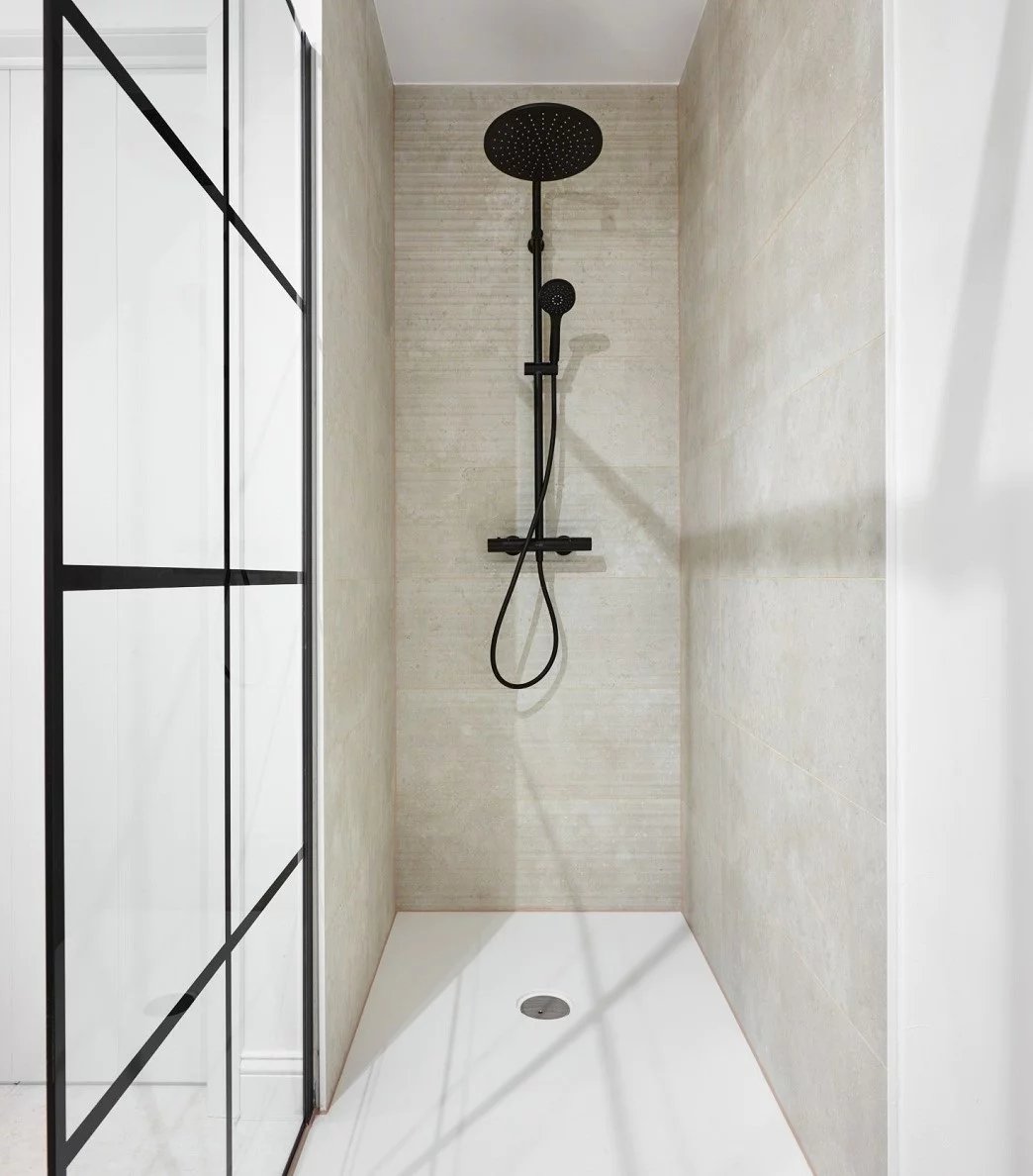 Douche à l'italienne moderne avec un panneau de douche noir et un mur en verre.