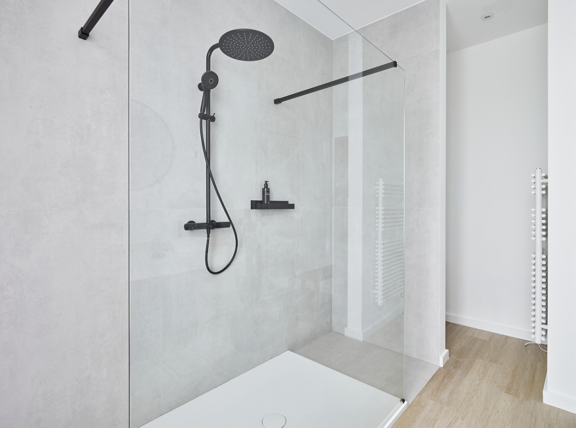 Cabine de douche moderne avec une douche à effet pluie noire et une paroi en verre minimaliste.