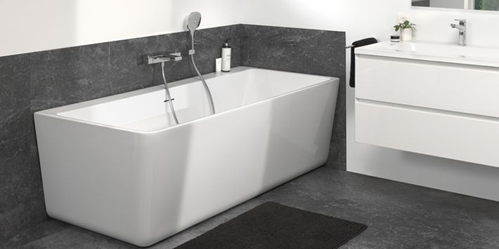 Moderne badkamer met vrijstaand bad, zwarte marmeren wand en wastafel met kranen.